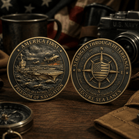 Two commemorative coins displayed on a wooden surface, one showing the front with an aircraft carrier and fighter planes, and the other showing the reverse with a compass and American flag motif. The coins are styled with vintage military props including a mug, camera, and compass.