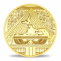 A round gold-colored commemorative coin featuring an Egyptian reed lion over a sarcophagus with hieroglyphic symbols, shown on a white background with a soft shadow.