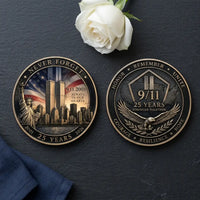 Overhead view of both 9/11 25th anniversary coin faces on charcoal slate, with a white rose above and navy linen at the lower left. The left shows the Twin Towers, Statue of Liberty and American flag beneath “NEVER FORGET,” with 2001–2026 anniversary dates. The right features a 9/11 shield above a spread-winged eagle, with “25 YEARS,” “STRONGER TOGETHER” and remembrance inscriptions around the rim, collectible token
