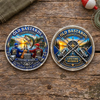 Two round metal fishing-themed coins displayed side by side on a rustic wooden surface. The left buckle features a colorful illustration of two fishermen, a large fish, and the text 'OLD BASTARDS FISHING CLUB V LIFETIME MEMBER THE LEGEND NEVER RETIRES'.