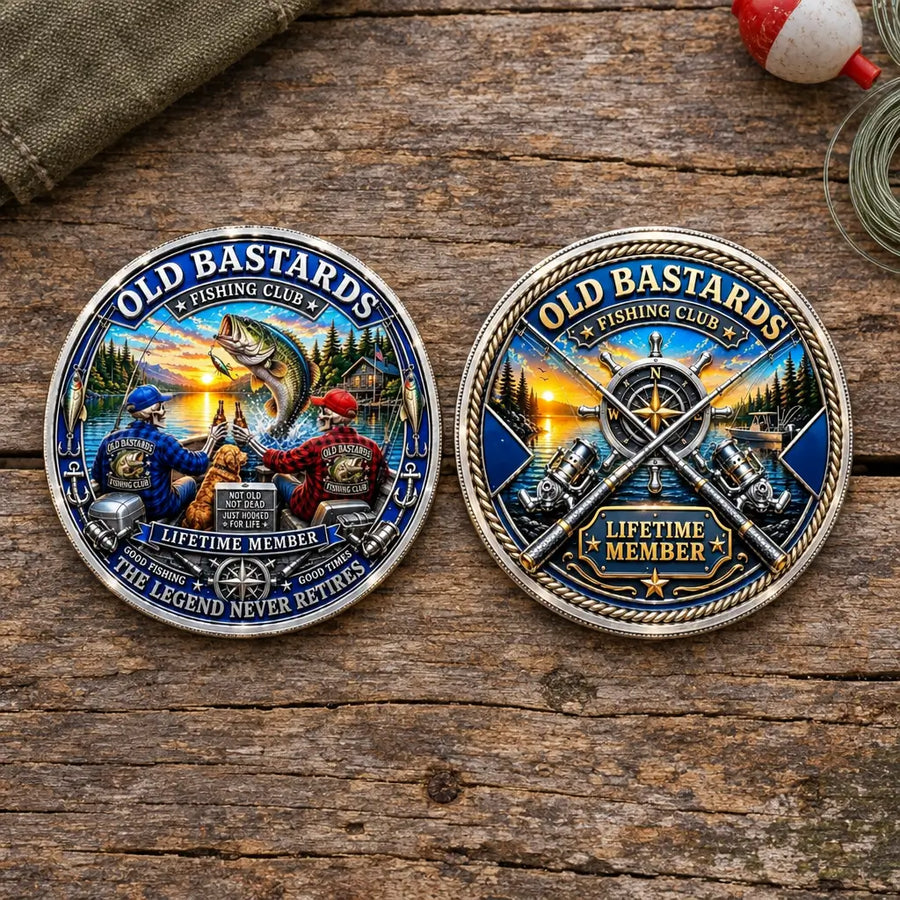 Two round metal fishing-themed coins displayed side by side on a rustic wooden surface. The left buckle features a colorful illustration of two fishermen, a large fish, and the text 'OLD BASTARDS FISHING CLUB V LIFETIME MEMBER THE LEGEND NEVER RETIRES'.