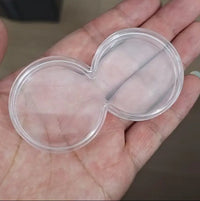 Hand holding clear acrylic double coin display capsule holder fits two 40mm coins transparent figure-eight coin storage accessory
