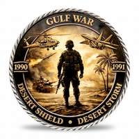 A circular commemorative coin or medallion featuring the text 'GULF WAR' at the top and 'DESERT SHIELD • DESERT STORM' along the bottom, with '1990' and '1991' on the sides. The design shows a soldier standing in a desert landscape with helicopters, a tank, palm trees, and military aircraft in warm brown, gold, and black tones. Available at one more coin store.