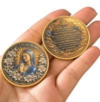 Two religious coins featuring Hail Mary, one showing a relief portrait of Mary and the other displaying the inscription, held in a person's hand against a black background.