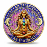 A circular gold-toned coin featuring a seated female figure with chakra symbols on her torso, surrounded by purple and pink floral patterns, crescent moons, stars, and the text 'I AM BALANCED' and 'I AM PROTECTED'. Available at one more coin store.