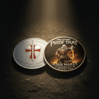 Two circular challenge coins displayed on a dark textured surface under dramatic spotlighting. One coin is silver-toned with a red and white cross emblem and the words 'TOLERANCE COURAGE COMPASSION INTEGRITY'.