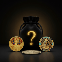 A black velvet drawstring pouch with a glowing gold question mark sits on a dark reflective surface, flanked by two ornate gold-toned coins featuring Egyptian-themed designs. A smaller silver-toned coin rests in front.