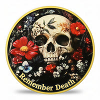 A circular decorative coin featuring a human skull surrounded by red, white, and blue flowers on a black background, with a gold border and the words 'Remember Death' in gold at the bottom. Available at one more coin store.