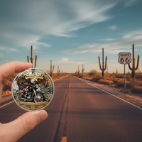 Hand holding Route 66 eagle motorcycle collectible coin against desert highway scene Route 66 road sign Arizona
