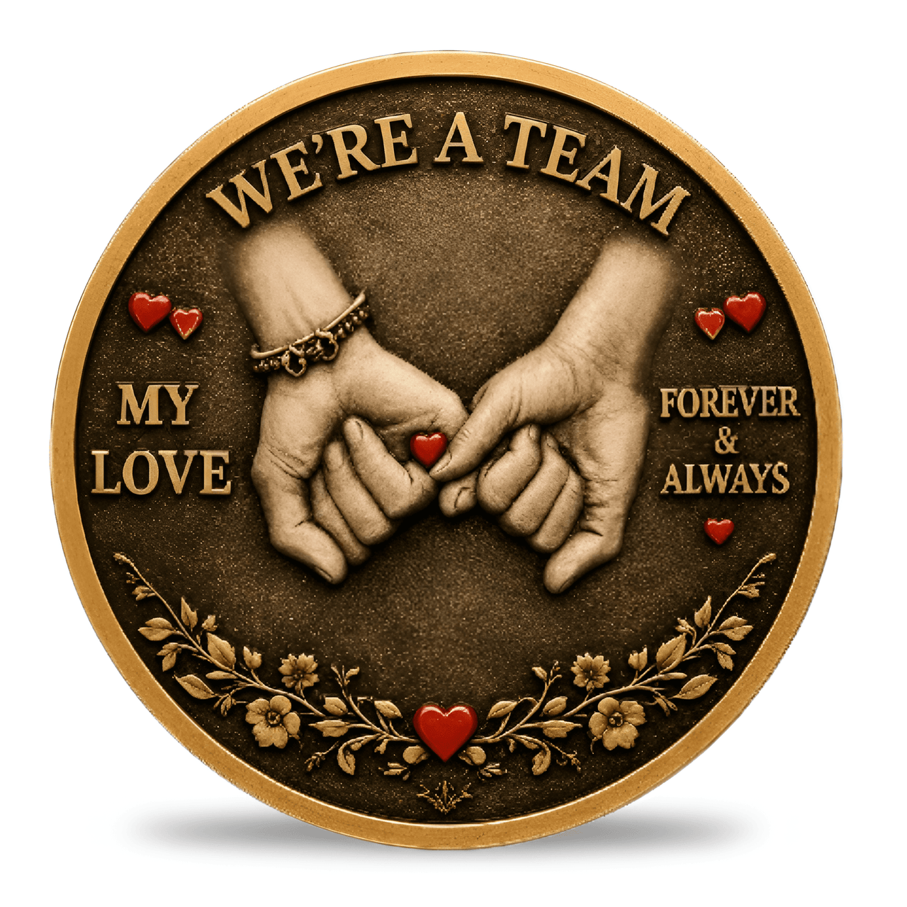 A round decorative coin with a bronze-toned background and raised gold border. The center shows two clasped hands with small red hearts, surrounded by the words “WE'RE A TEAM,” “MY LOVE,” and “FOREVER & ALWAYS,” with floral details along the bottom.